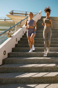 Young athletic women in sportswear are jogging around the city in early morning. Reaching the goal