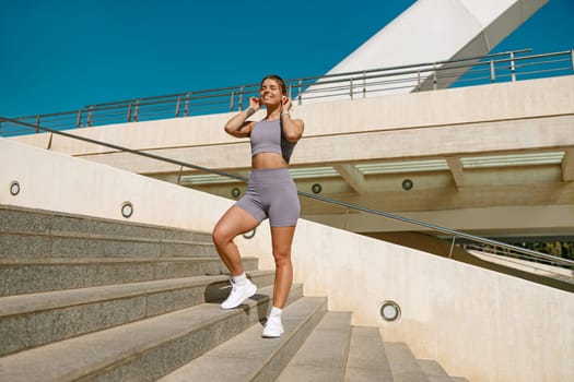 Smiling woman in sportswear have a rest after workout outside standing on bridge background