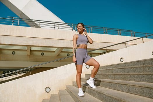 Female athlete in sportswear have a rest after morning jogging outside and looks away