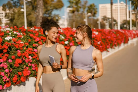 Smiling female sportswomen have a rest after morning jogging outdoors