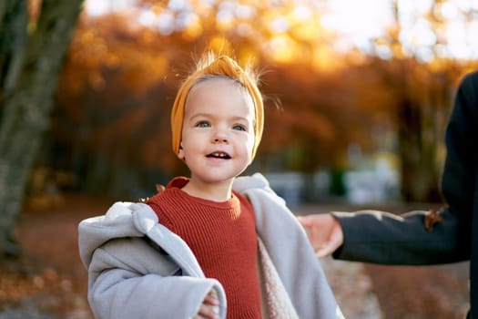 Mom touches the shoulder of a little girl standing in the autumn park. Cropped. High quality photo