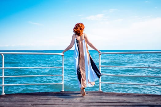 Behind girl on pier. Beautiful red head woman on the pier at the sea.