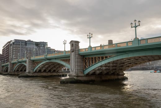 London, UK - Feb 27, 2024 - View of Southwark Bridge cross The River Thames in London. The side of a turquoise cast iron bridge, Curved steel Bridge, Space for text, Selective focus.