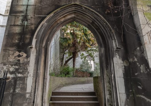 London, UK - Feb 27, 2024 - The stone arched entrance leads to the stone staircase inside of St Dunstan in the East Church Garden. The historic church was bombed and destroyed in the Second World War and is now a park, London city hidden places, Space for text, Selective focus.