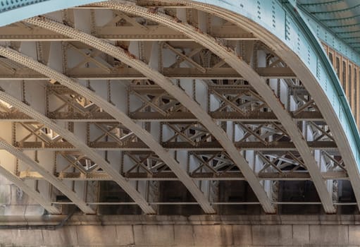 London, UK - Feb 27, 2024 - Detail of Structure and Girders supporting underneath Southwark Bridge Over The River Thames in London. The side of a turquoise cast iron bridge, Curved steel Bridge, Space for text, Selective focus.