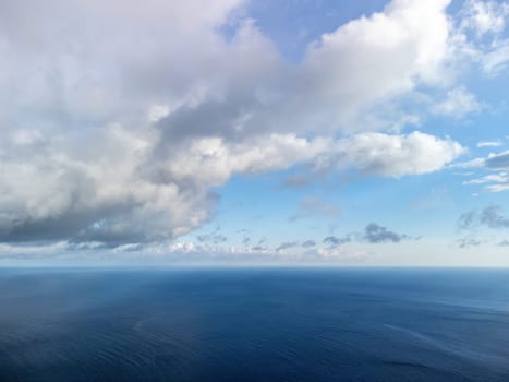 Blue sky with white clouds over calm summer panorama of the sea. Drone aerial view. Abstract aerial nature summer ocean sunset sea and sky background. Horizon. No people. Holiday and vacation concept