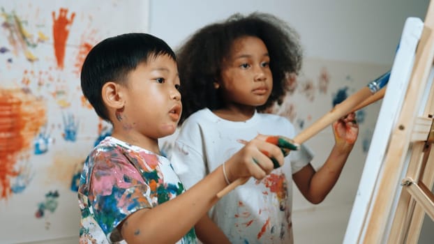 Happy creative african girl painted or draw canvas together with asian boy. Group of playful student create funny painting or artwork painted by watercolor. Creativity activity concept. Erudition.