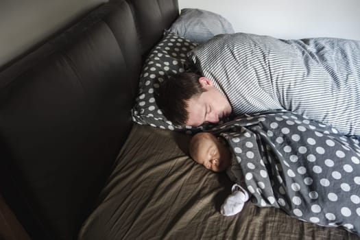 Father sleeping peacefully with a newborn baby in a bed