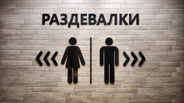 Male and Female Restroom Symbols on Wooden Wall With Directional Arrows. Gender-specific bathroom signs on wood surface