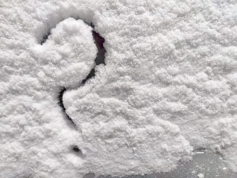 Question mark written in the snow. The cold frosty texture of the snow and the question mark. Background, place for text, copy space