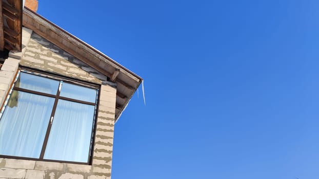 Sharp icicles from melted snow hanging from eaves of roof. Beautiful transparent icicles. Icicles on eaves of the house