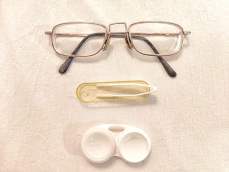 Set for contact lenses with a container, forceps, glasses. The concept of correcting myopia. Contact lens care, cleaning, health. Background, copy space