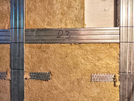 Wall Insulation Process With Precision Markings in a Building. Insulation material installed on wall, secured with measured metal brackets