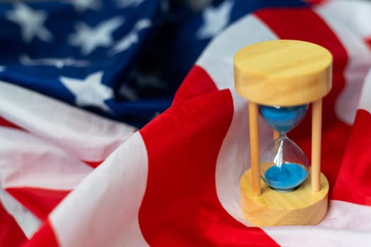 Hourglass and USA flag, soft focus, copy space. High quality photo