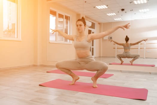 Girl does yoga. Young woman practices asanas on a beige one-ton background