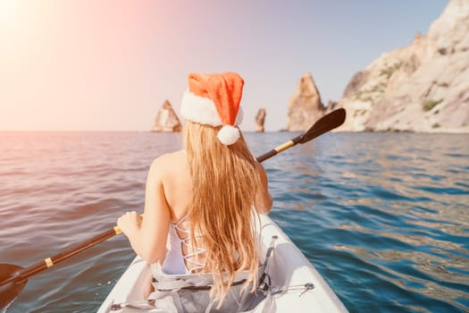 Woman in kayak back view. Happy young woman with long hair floating in transparent kayak on the crystal clear sea. Summer holiday vacation and cheerful female people relaxing having fun on the boat