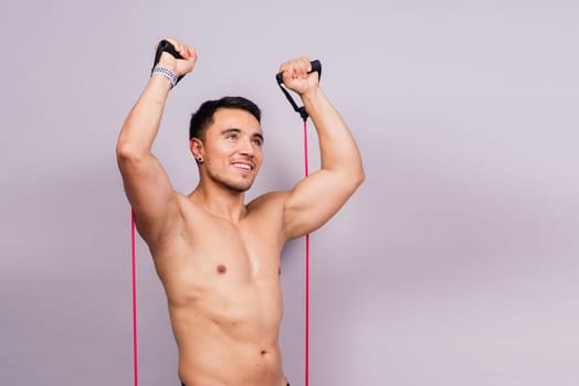 Young handsome man during workout with resistance rubber bands. Shoulder lateral raise exercise.