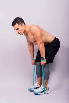 Young handsome man during workout with resistance rubber bands. Shoulder lateral raise exercise.