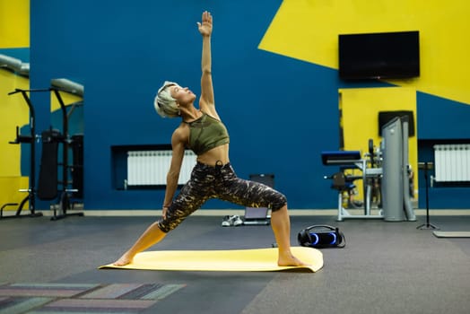 slender athletic woman in the gym is beautifully engaged in yoga exercises on a mat