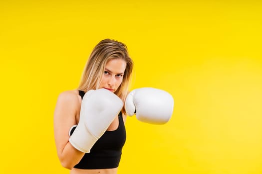 Female boxer hitting at boxing studio. Woman in gloves training hard.