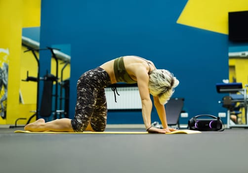 slender athletic woman in the gym is beautifully engaged in yoga exercises on a mat