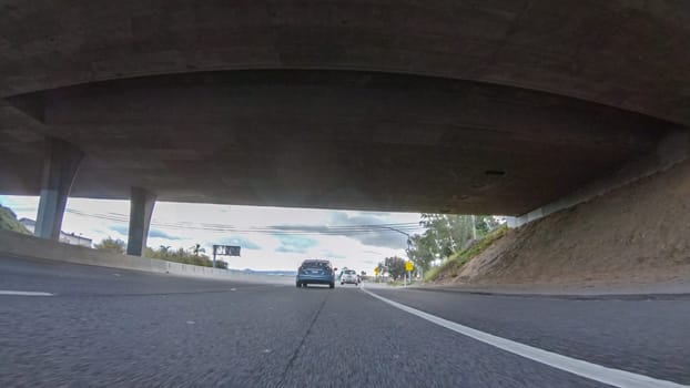 Santa Maria, California, USA-December 6, 2022-On a cloudy winter day, a car smoothly travels along Highway 101 near Santa Maria, California, under a cloudy sky, surrounded by a blend of greenery and golden hues.