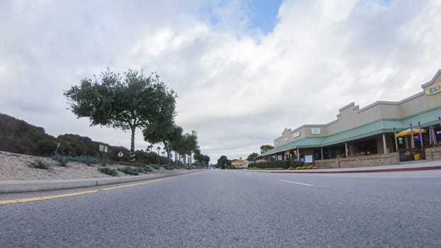 Santa Maria, California, USA-December 6, 2022-Vehicle navigates the streets of Morro Bay, California, during a cloudy winter day. The atmosphere is moody and serene as the overcast sky casts a soft light on the charming buildings and quiet streets of this coastal town.