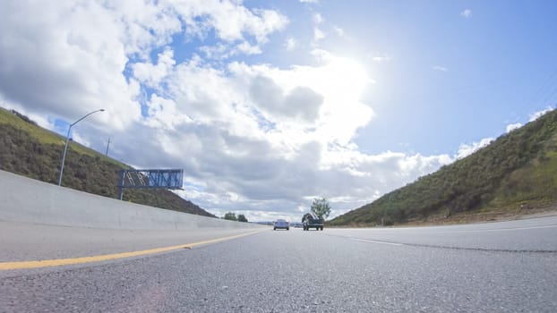 Santa Maria, California, USA-December 6, 2022-On a clear winter day, a car smoothly travels along Highway 101 near Santa Maria, California, under a brilliant blue sky, surrounded by a blend of greenery and golden hues.