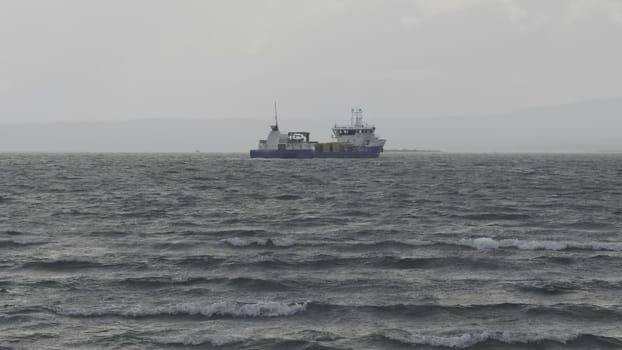 Fishing boat endures rough seas and cloudy weather, conveying a grim day at sea.