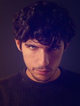 A close up, head shot of a handsome young man with green eyes, wearing a black shirt, looking at camera