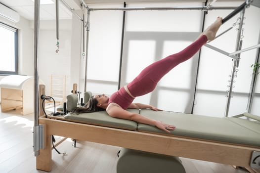 Woman doing pilates exercise on cadillac reformer machine