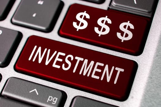 Investment text and dollar symbol on red laptop keyboards. Business investment concept.