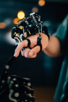 In a technical college a teenage boy learns technology testing a robot hand and arm touching fingers for educational skill enhancement. Embracing futuristic AI and humanity.