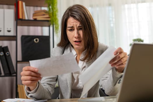Caucasian businesswoman girl opening envelope reading bad news in letter feels upset sitting at home office table. Financial problems, bank debt bill for pay, tax invoice or bankruptcy notification.