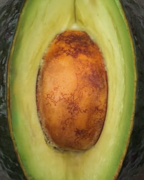 Macro shot of an avocado half with the seed in focus, showcasing the fruit's texture and color contrasts