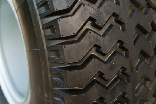 Detailed view of a tire mounted on a vehicle, showcasing the tread pattern and sidewall. The tire is dirty, indicating recent use.