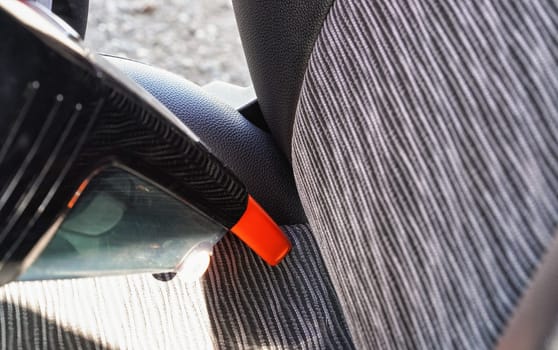 Car interior - seats, cleaned from dust with small orange portable vacuum cleaner