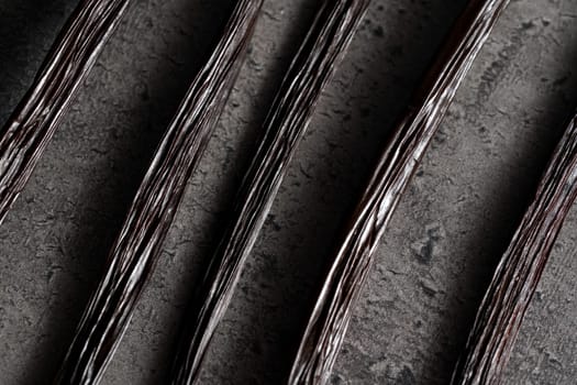 Vanilla beans over dark grey stone like board - closeup macro photo