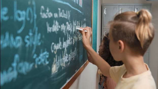 Diverse student studying coding engineering prompt while writing answer on blackboard. Intelligence children planning and learning about coding development plan. Successful boy sharing idea. Pedagogy.