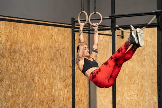 Strong female mature athlete using rings in a cross training gym