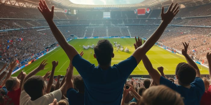 A lively crowd of fans with arms raised enthusiastically watch a soccer game in a vibrant stadium, amidst the green grass of a sport venue. AIG41