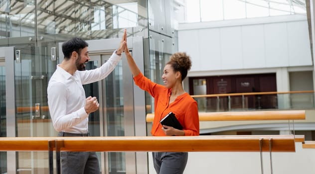 Two young businesspeople smiling while working with wireless technology in a modern workspace.