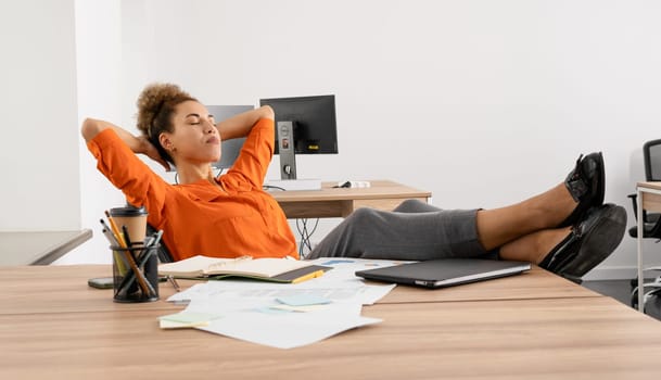 Young busy African business woman executive working on laptop making call at office.