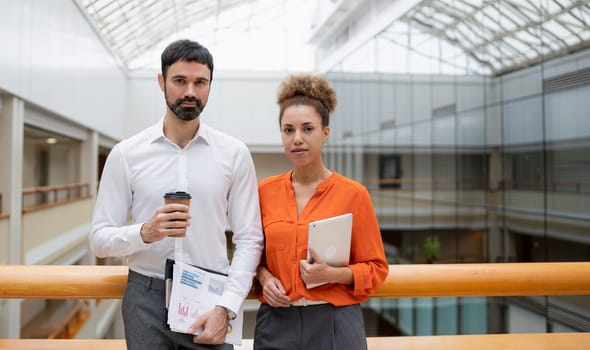 Two young businesspeople smiling while working with wireless technology in a modern workspace.