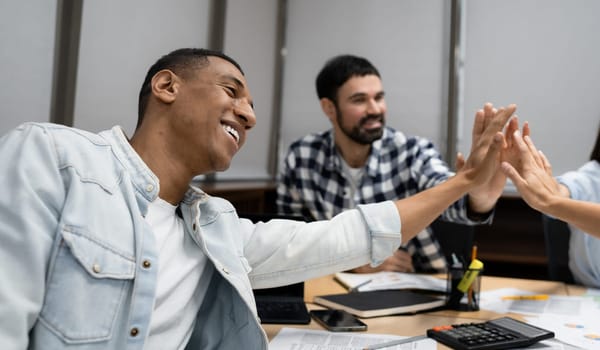 Group of diverse businesspeople using a laptop while working together in a modern workspace.