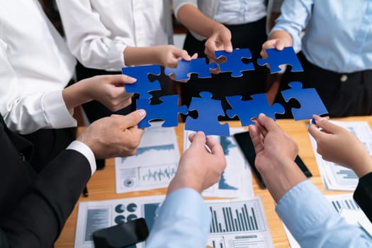 Multiethnic business people holding jigsaw pieces and merge them together as effective solution solving teamwork, shared vision and common goal combining diverse talent. Meticulous