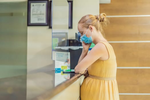 A pregnant woman stands at the hospital reception desk, embarking on a crucial phase of her maternity journey, seeking care and support in a healthcare setting.