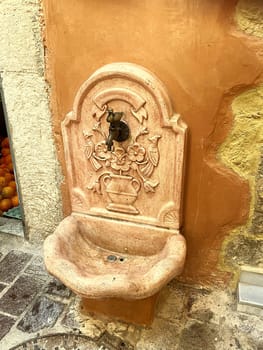 Antique marble water fountain on a stone wall in the historic center of Creta, Chania, Greece at 10 August 2023. High quality photo