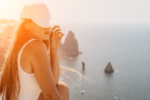 Woman travel sea. Young Happy woman in a long red dress posing on a beach near the sea on background of volcanic rocks, like in Iceland, sharing travel adventure journey