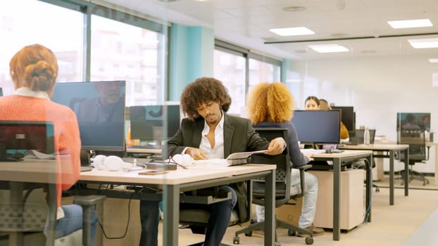 Team of multiethnic young coworkers working with computers on desks